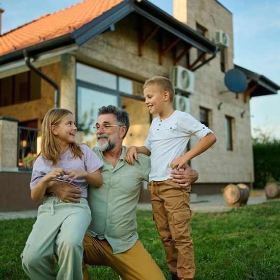 Grandfather and grandchildren happily playing in backyard on sunny summer day, surrounded by lush green grass, radiating love and joy